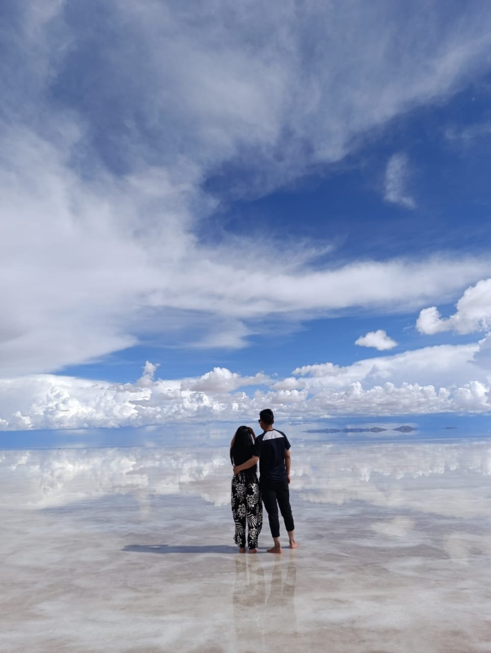 Viajero caminando sobre el Salar de Uyuni en Bolivia, con el cielo reflejado en la superficie blanca de sal.