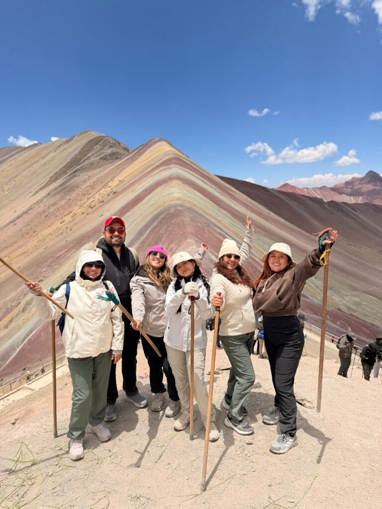 Grupo de viajeros explorando un paisaje de montañas rojizas y ocres bajo el cielo azul de los Andes.