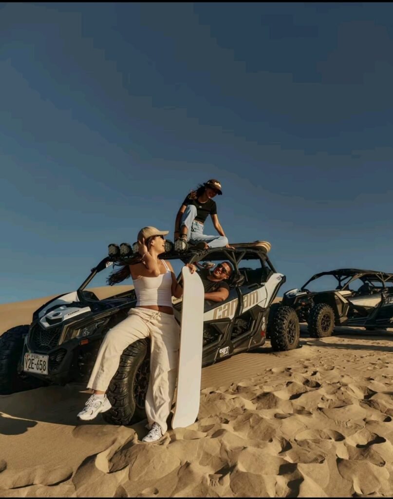 Personas practicando sandboarding junto a carritos areneros en las dunas del desierto de Ica, Perú. Copiar ALT