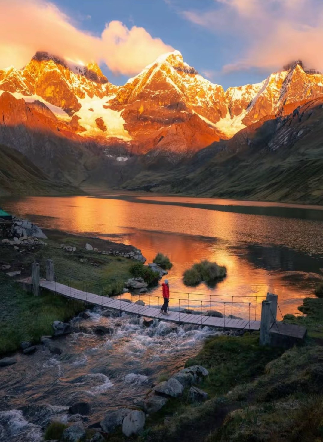 Paisaje de la Cordillera Huayhuash en Áncash, Perú, con nevados iluminados al atardecer y una laguna rodeada de montañas.