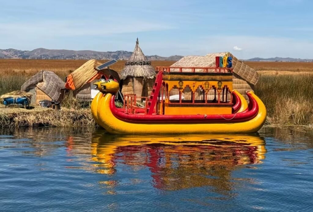 Embarcación tradicional navegando junto a las islas flotantes de los Uros en el lago Titicaca, Puno, Perú.
